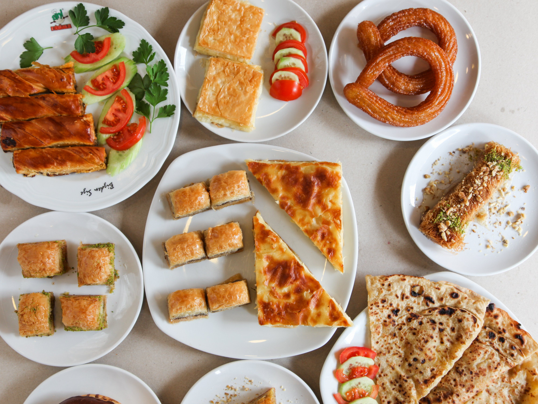 Verschiedene türkische Backwaren auf weißen Tellern, darunter Baklava und Börek.